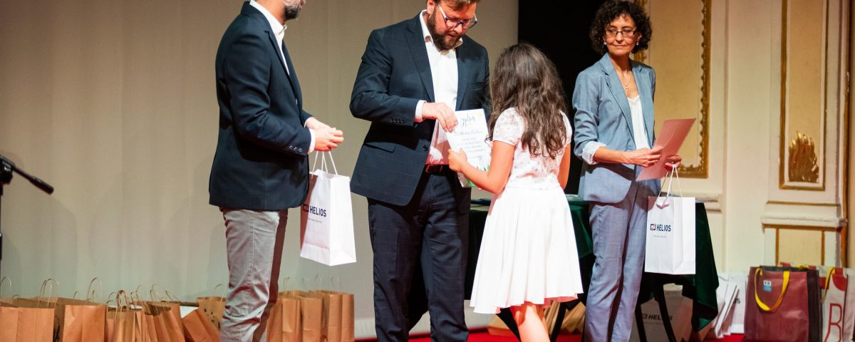 Zdjęcie dziewczynki w sukience odbierającej nagrodę